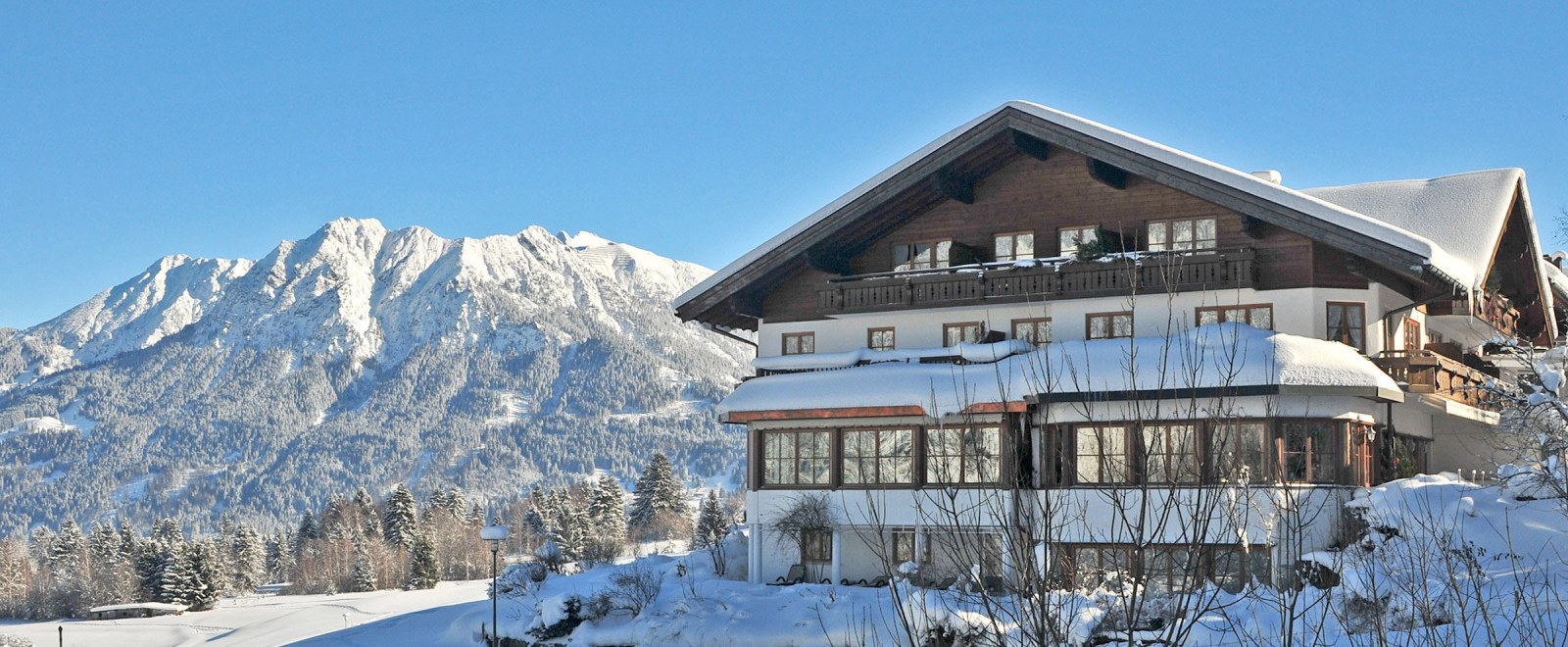 Hotel vor verschneitem Bergpanorama